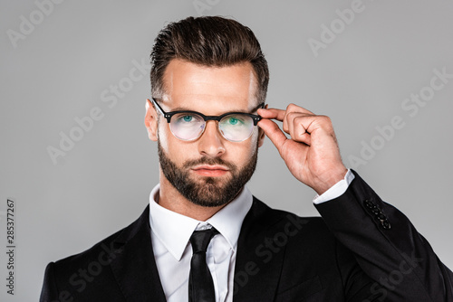 successful businessman in black suit and glasses isolated on grey