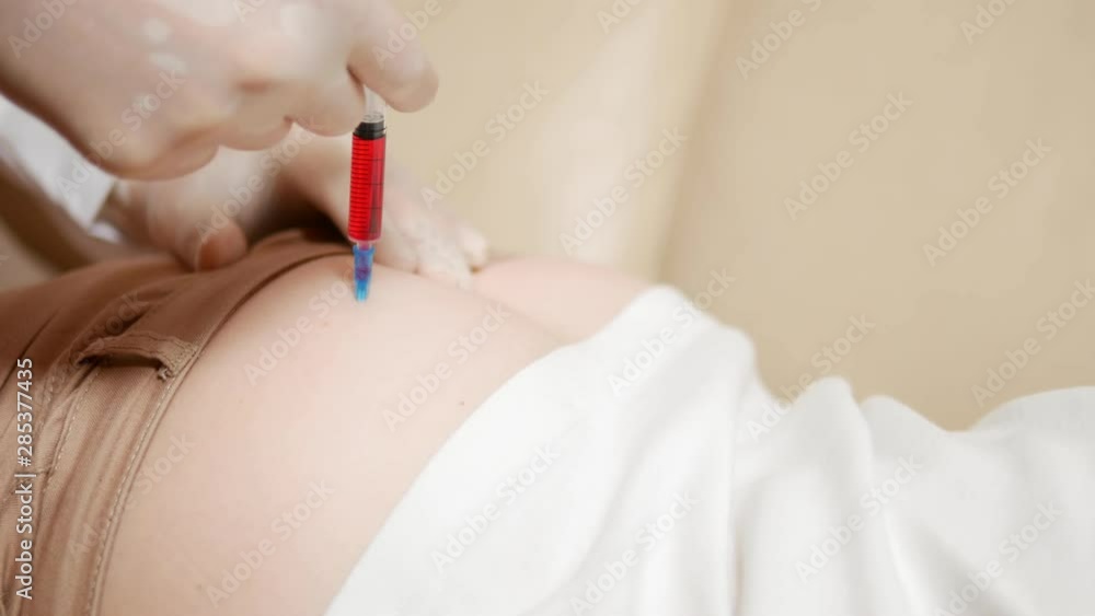 close-up, the doctor puts an injection into the buttock of the patient. close-up, the doctor puts an injection into the buttock of the patient.