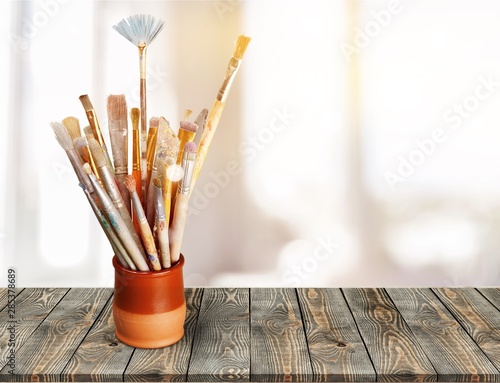 Brushes in glass jar on wooden desk