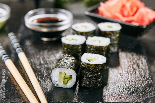 Obraz na plátně Macro shot of hosomaki sushi with soy sauce on natural black slate plate background with selective focus