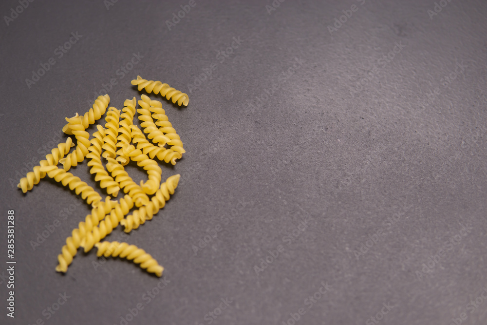 Raw pasta in the form of a spiral on grey background Raw pasta in the form of a spiral on grey background