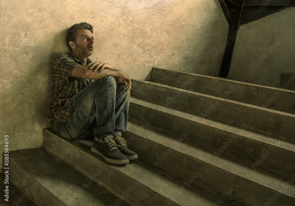 desperate man sitting outdoors on dark grunge street corner staircase feeling sick suffering depression problem and anxiety crisis in mental health concept