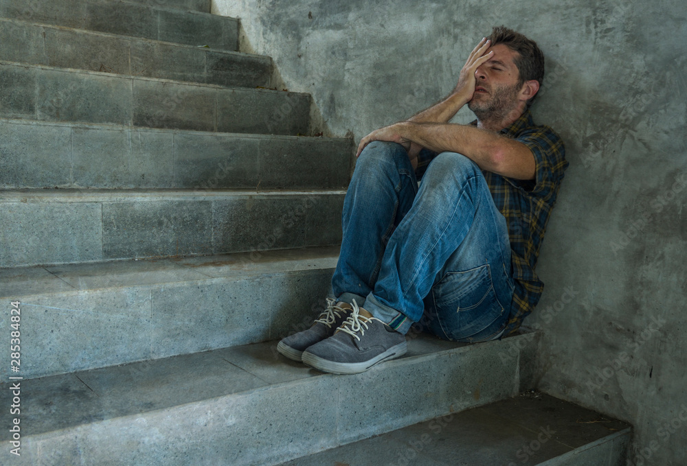 dramatic portrait of young depressed and desperate man sitting outdoors on dark grunge street corner staircase feeling sick suffering depression problem and anxiety crisis dramatic portrait of young depressed and desperate man sitting outdoors on dark grunge street corner staircase feeling sick suffering depression problem and anxiety crisis