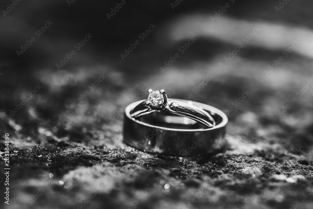 Close up of two wedding rings on the ground. Symbol of commitment. Black and white photo. Close up of two wedding rings on the ground. Symbol of commitment. Black and white photo.