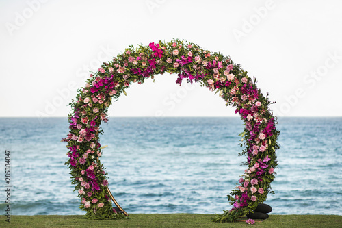 Canvastavla Wedding round arch decorated with beautiful colorful orchid and rose flowers on the beach