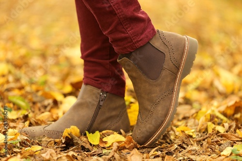 Autumn time. Autumn shoes . Female legs in brown boots on yellow maple leaves. 