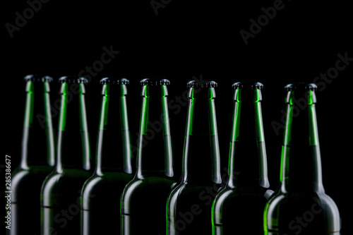 Row of glass bottles of beer on dark background