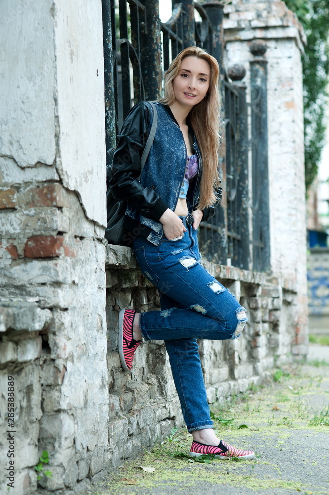 Beautiful sexy young blond woman in torn jeans posing on the streets of the old town