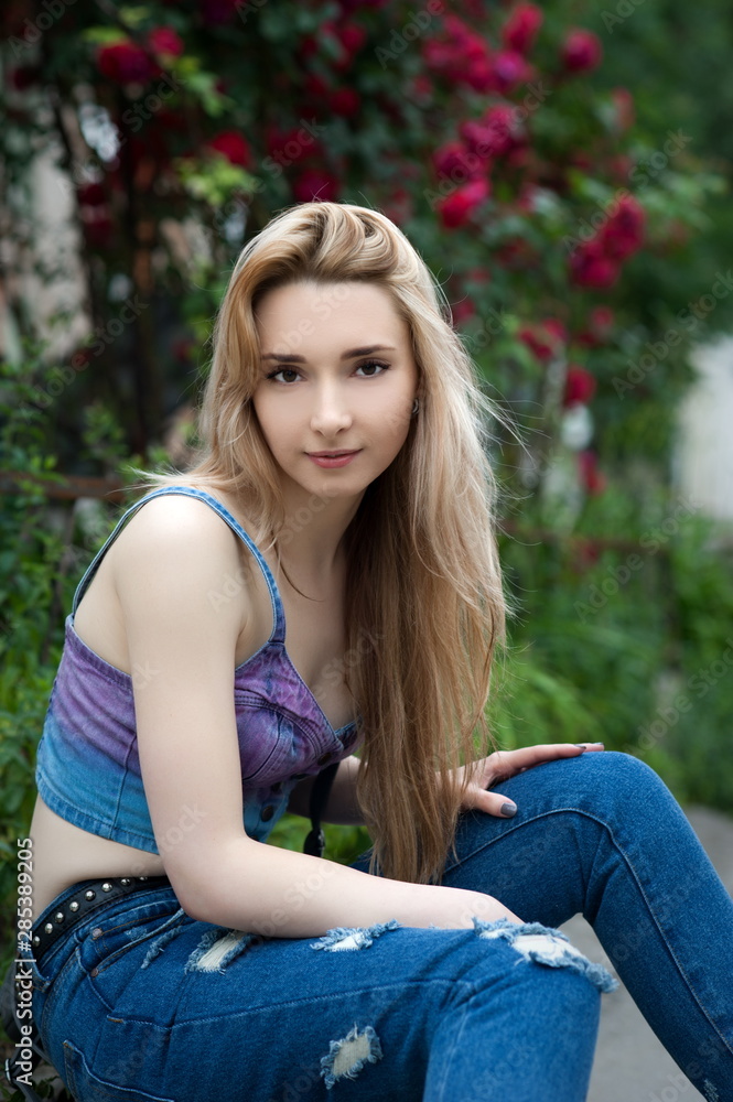 Obraz premium Beautiful sexy young blond woman in torn jeans posing on the streets of the old town