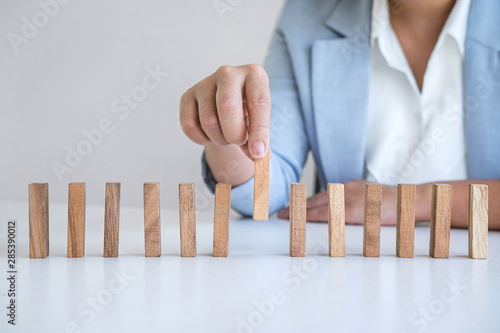 Risk and Strategy in Business, Image of hand gambling placing wooden block on a line of domino, prevention and development to stability