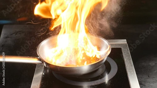 Chef cooking flambe dish in restaurant kitchen. Italian cuisine. Food video in slow motion. Magnificent flame over frying pan. Flambe fruit dessert. hd