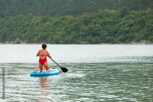 Young girl floating on a Board La sup surfing on the lake.