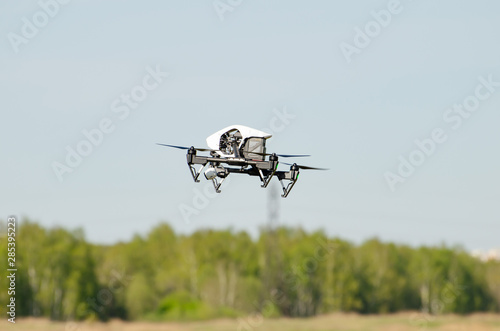 white quadcopter in the air against the forest and sky