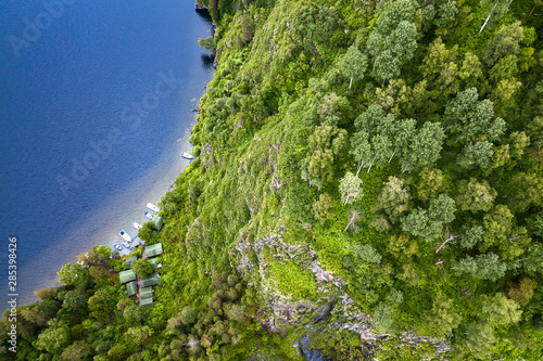 An aerial view of the Teletskoye Lake between the Altai Mountains on the shore on which there are green trees and other ships Fototapete