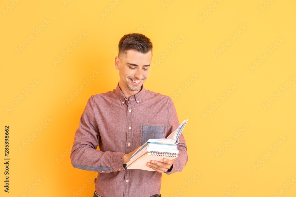 Handsome male teacher with books on color background Handsome male teacher with books on color background