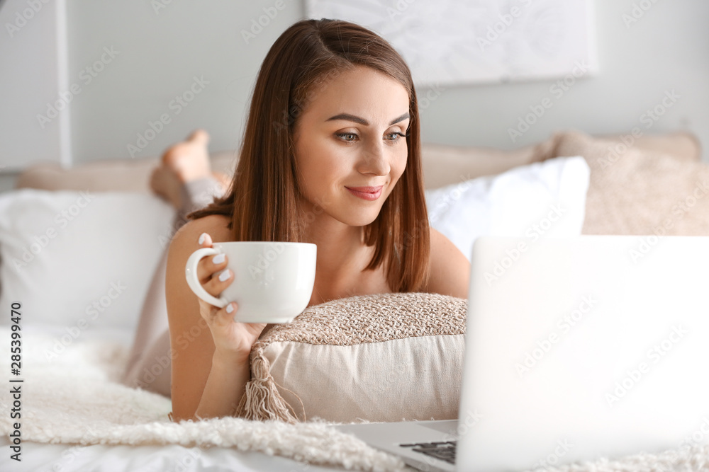 Beautiful young woman with laptop drinking tea at home Beautiful young woman with laptop drinking tea at home