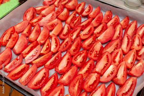 Homemade dried red  tomatoes slices with basil oregano spices cooking process. Traditional Italian Mediterranean kitchen cuisine.