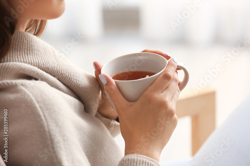 Photo Beautiful young woman drinking tea at home, closeup