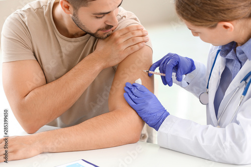 Doctor vaccinating young ma...