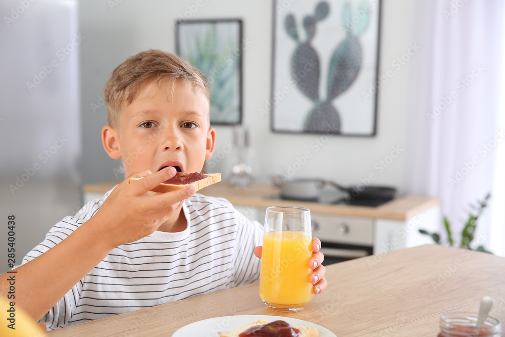 Funny little boy eating tasty toasts with jam in kitchen Funny little boy eating tasty toasts with jam in kitchen