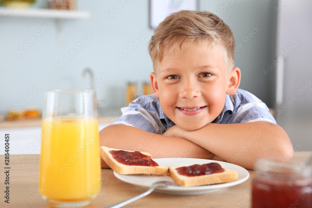 Funny little boy eating tasty toasts with jam in kitchen Funny little boy eating tasty toasts with jam in kitchen