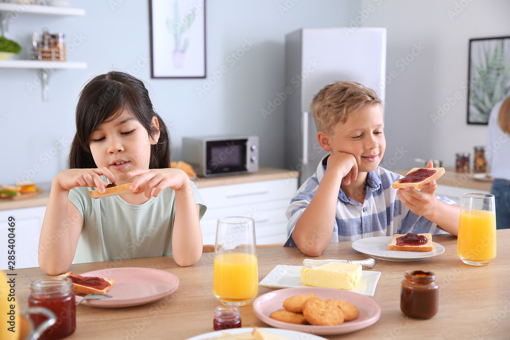 Funny little children eating tasty toasts in kitchen Funny little children eating tasty toasts in kitchen