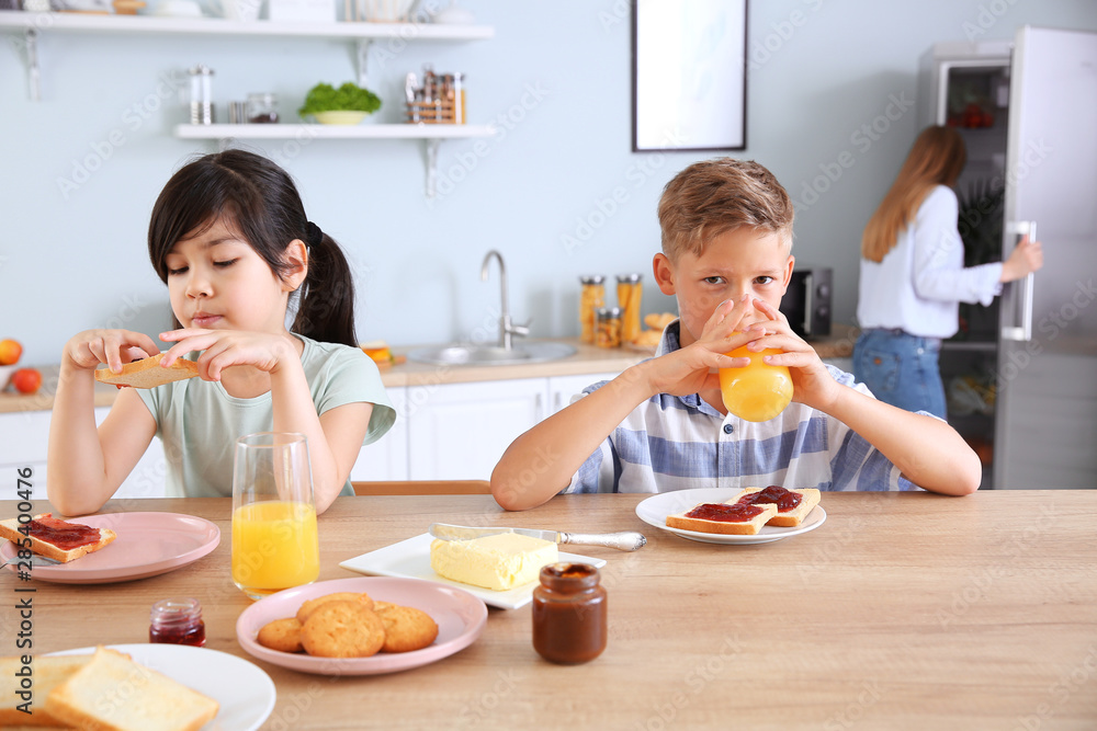 Funny little children eating tasty toasts in kitchen Funny little children eating tasty toasts in kitchen