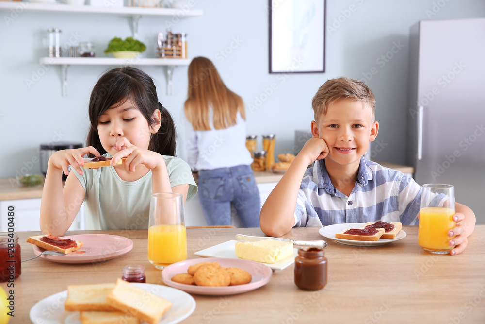 Funny little children eating tasty toasts in kitchen Funny little children eating tasty toasts in kitchen
