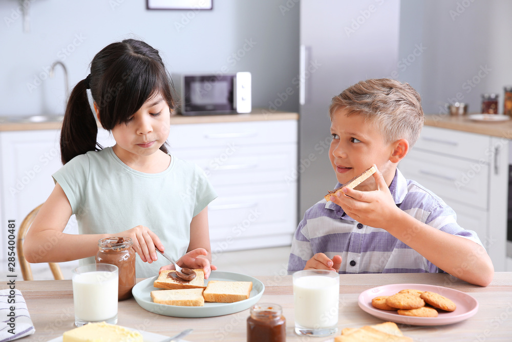 Funny little children eating tasty toasts in kitchen Funny little children eating tasty toasts in kitchen