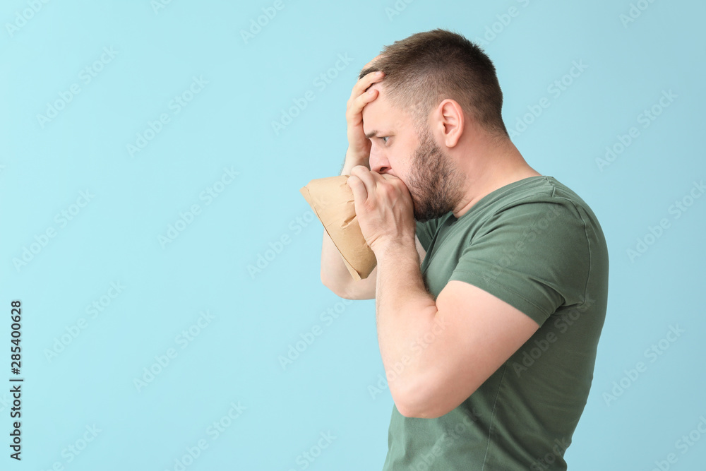 Man with paper bag having panic attack on color background Man with paper bag having panic attack on color background