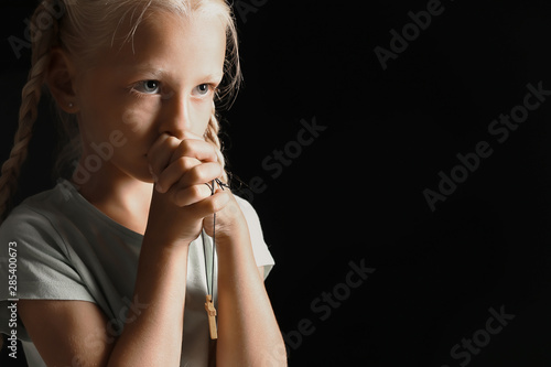 Little girl praying on dark...