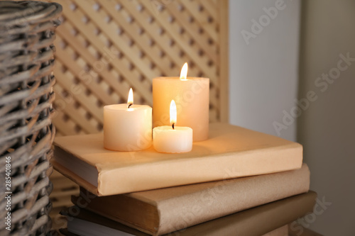 Beautiful burning candles and books on table