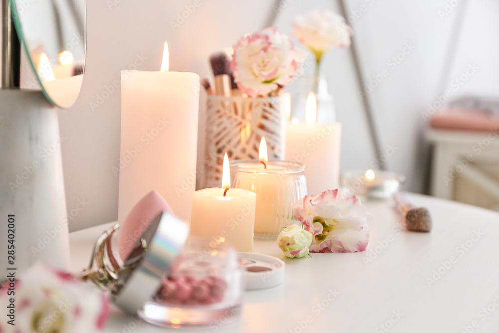 Beautiful burning candles and cosmetics on dressing table