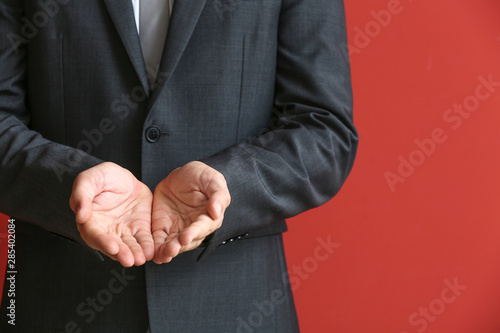 Businessman holding something against color background, closeup