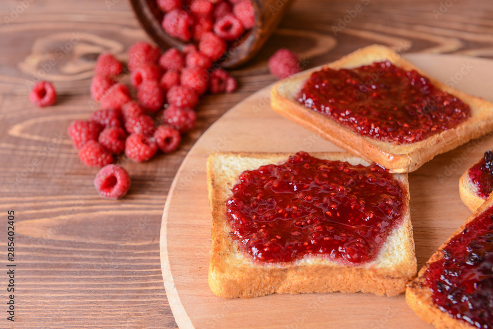 Tasty toasted bread and raspberry jam on wooden board Tasty toasted bread and raspberry jam on wooden board