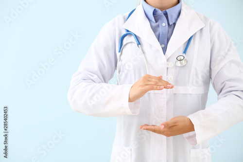 Doctor holding something on color background
