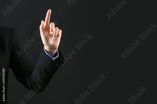 Hand of businesswoman pointing at something on dark background