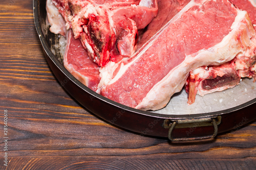 Red Meat Chunk And Steak in grunge pan On Wood Table. Organic Red Raw Steak