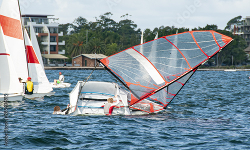 Fotografie Children climbing back into a capsized sailboat with on an inlan