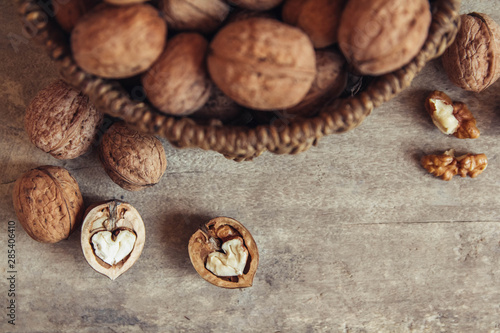 Walnuts in a round wicker basket on a wooden background. Top view. Copy, empty space for text