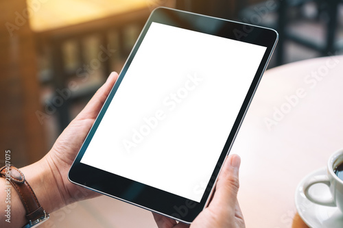 Mockup image of hands holding black tablet pc with blank white desktop screen