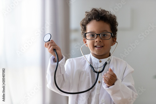 Slika na platnu Cute african kid boy wear medical uniform playing doctor, portrait