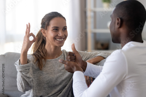 Happy mixed race deaf couple using sign language for communication photo