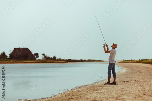 Young man fishing at sea from the shore. fisherman uses spinning