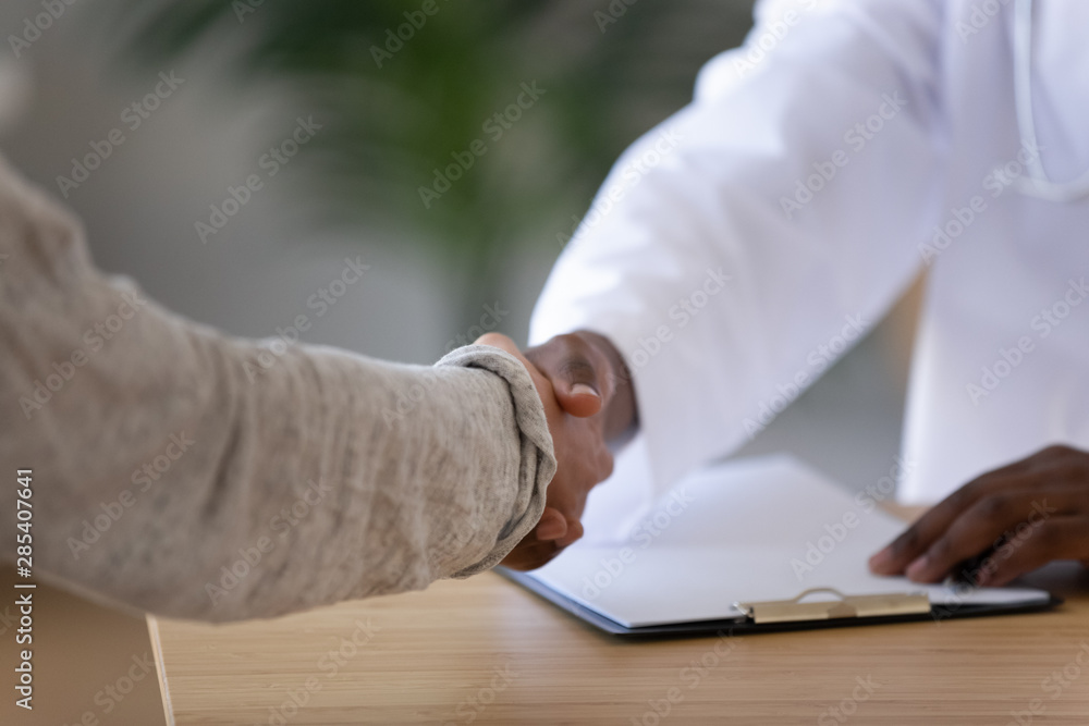Male black doctor handshake female white patient, close up view Male black doctor handshake female white patient, close up view