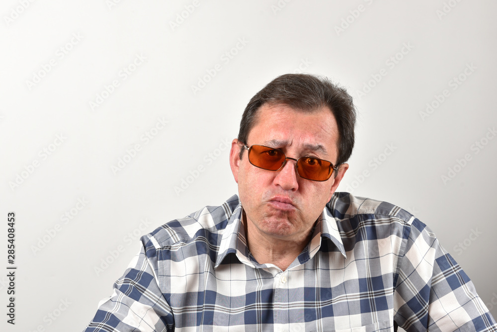 Obraz premium Portrait of a mature man in glasses, a plaid shirt on a white background. Emotions and gestures.