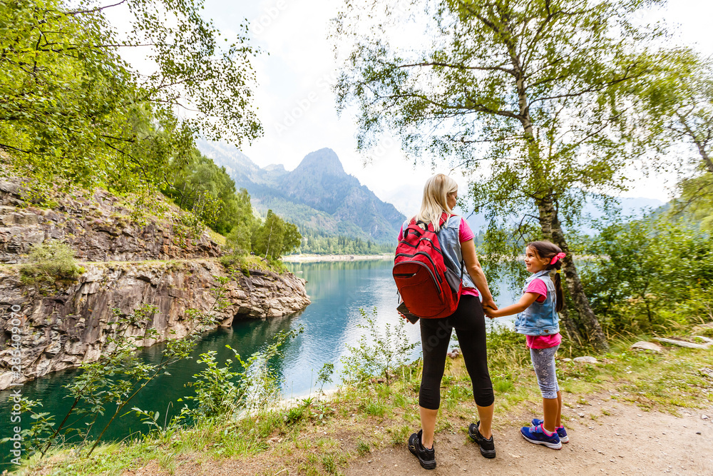 Hikers with backpack looking at mountains, alpine view, mother with child