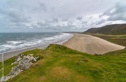 Rhossili bay on the West Wales Coast on the Gower Peninsula on a windy, blustery day in Summer with the white waves rolling in. Wales.