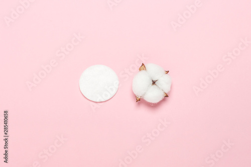 Cotton hygienic make-up disk and cotton flower on a pink background. Makeup and hygiene concept, natural product. Flat lay, top view