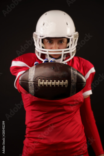 Picture of american woman football player in helmet with arm outstretched forward